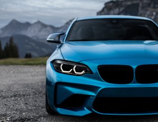 Front view of a blue sports car with mountains in the background.