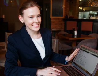A professional-looking lady is holding a laptop with smile on her face.